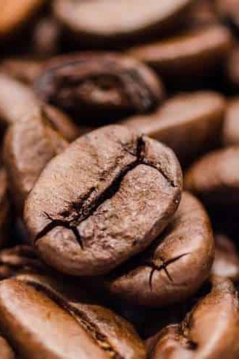 Close-up of roasted coffee beans with rich, dark brown tones, showcasing their texture and natural oils. Perfect for illustrating high-quality Arabica coffee from Rwanda.